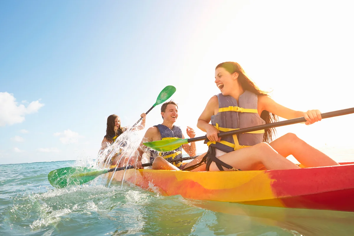 Siblings rowing canoe in the ocean