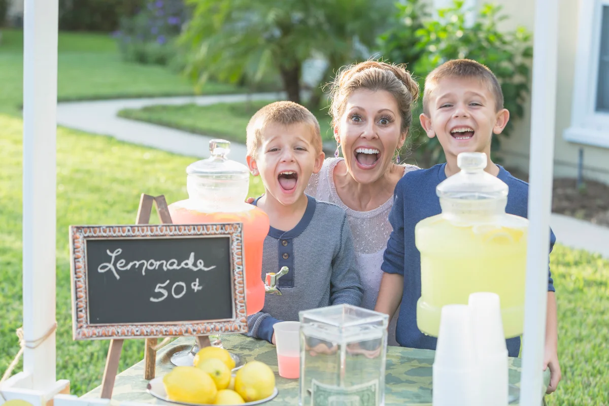 Two boys with their mother selling lemonade from their stand