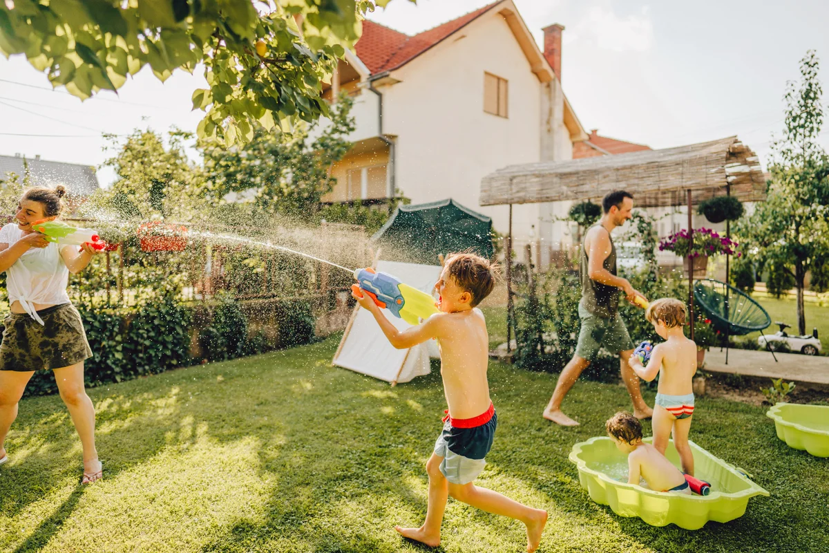 Happy family enjoying in a water fight in their yard