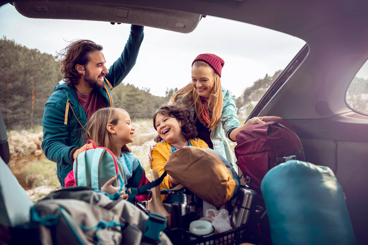 Young family getting the camping supplies out of the car