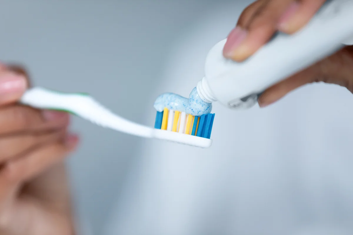 woman applying toothpaste on toothbrush