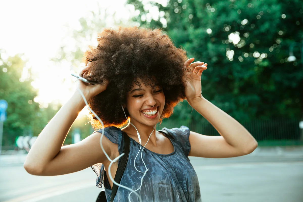 Young woman dancing in the city at sunset while listening to music