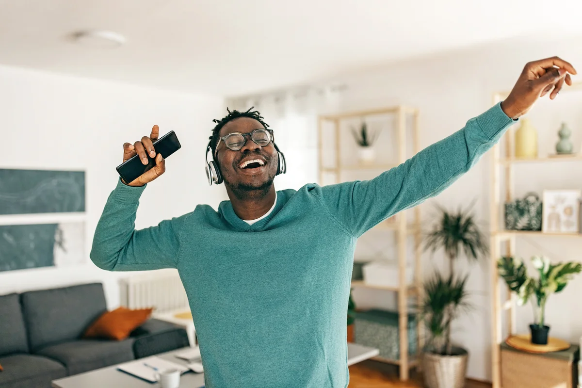 Young man dancing while holding his mobile phone and listening to the music
