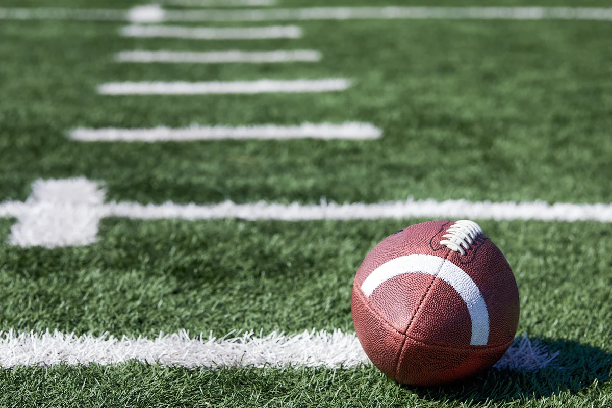 American football ball at yard line markers on playing field
