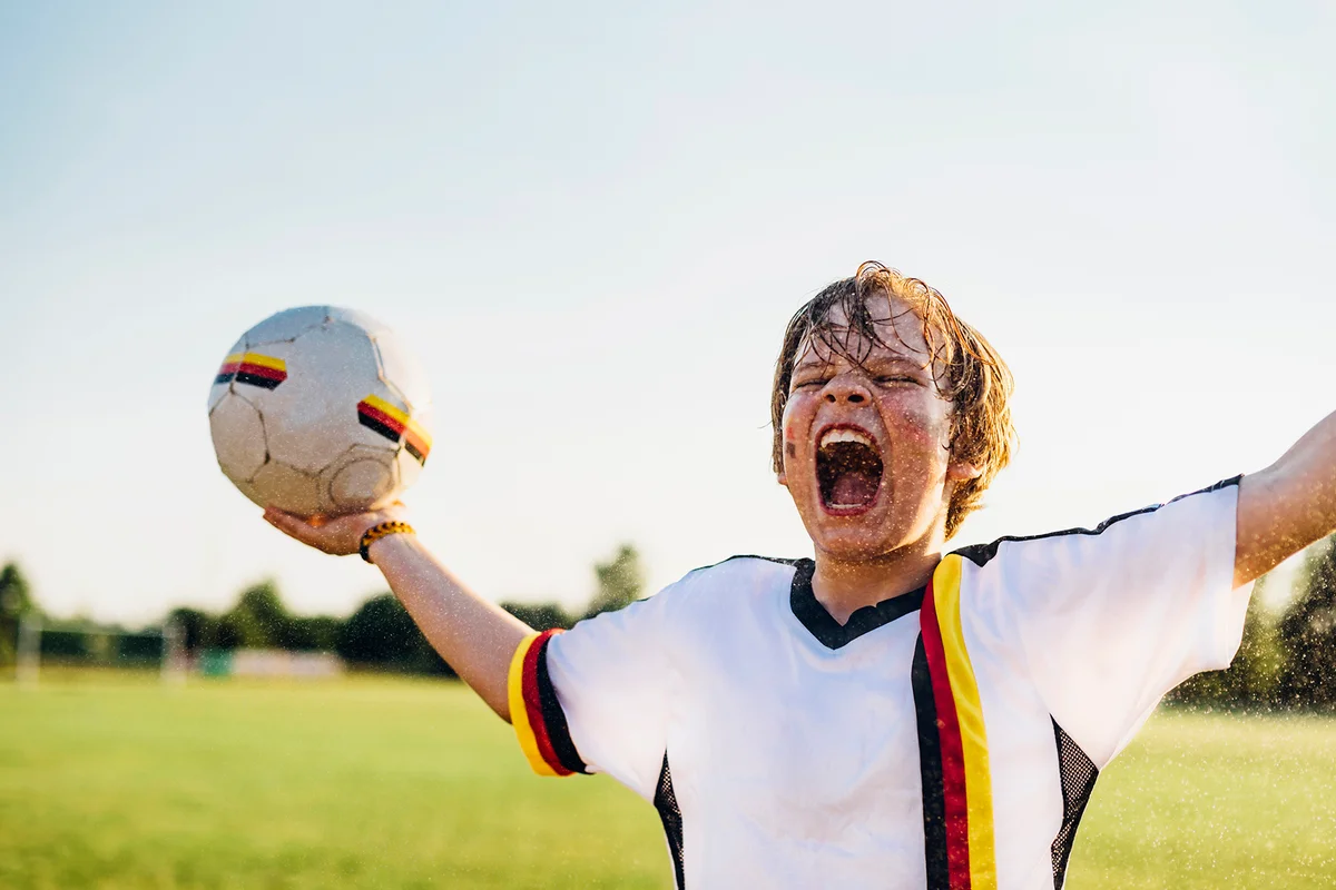 Boy wearing German soccer shirt screaming for joy