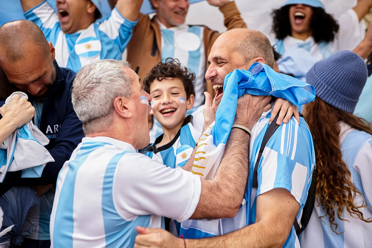 Argentinian football fan friends and little boy celebrating goal
