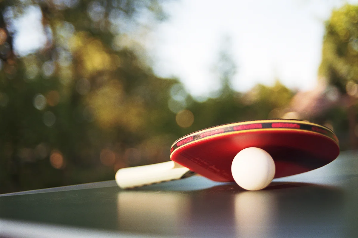 Table tennis paddle and ball on table outdoors