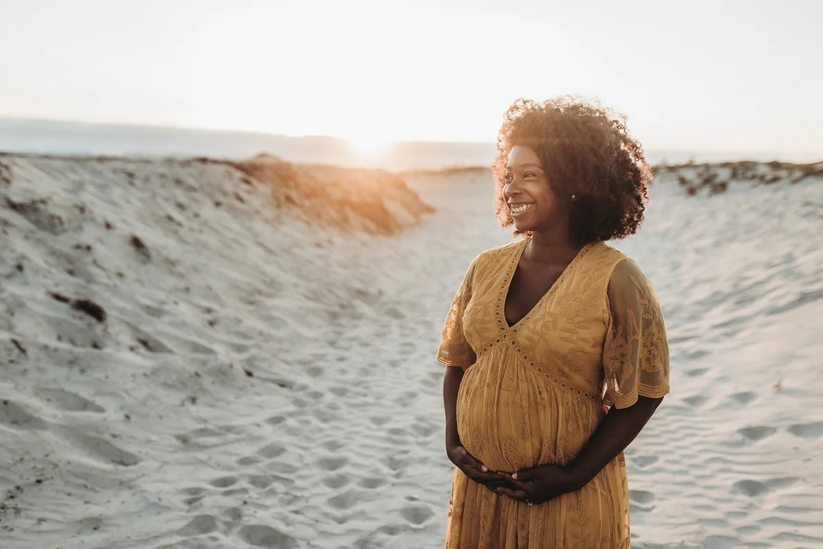Portrait of pregnant mother in third trimester at beach at sunset