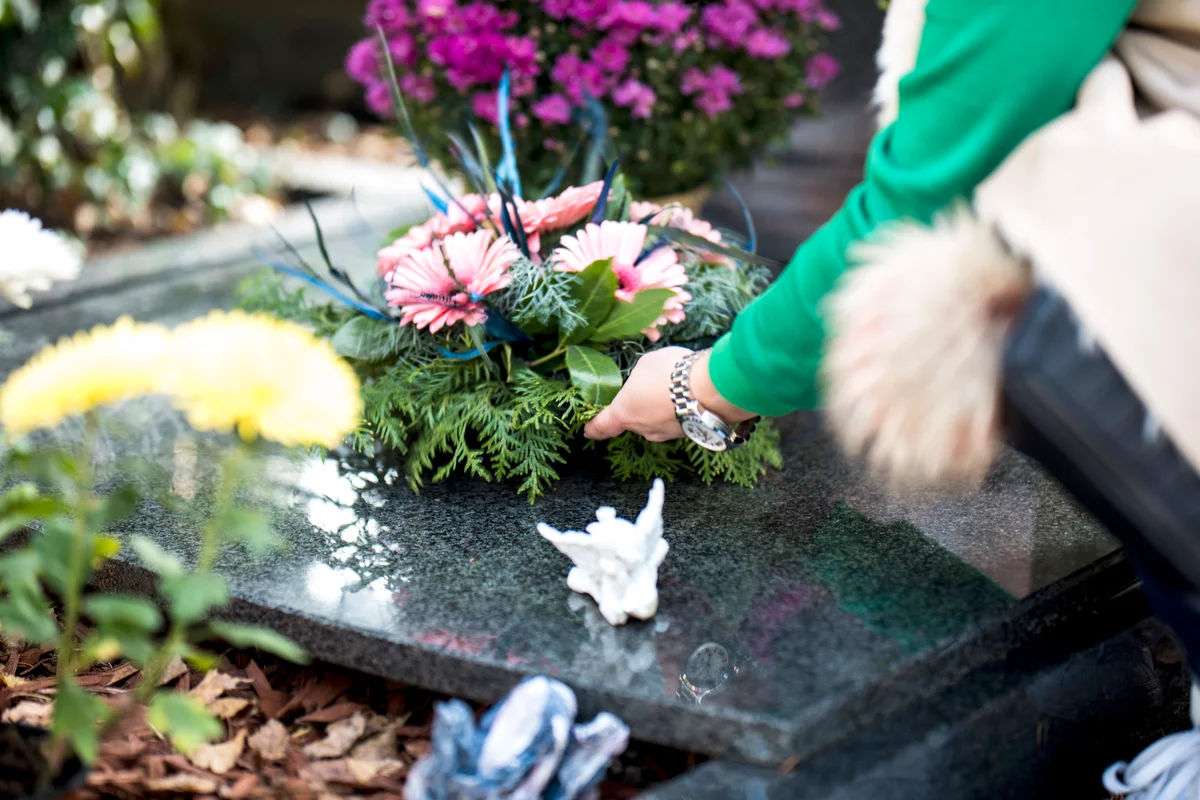 Woman putting flowers and ornaments in a grave