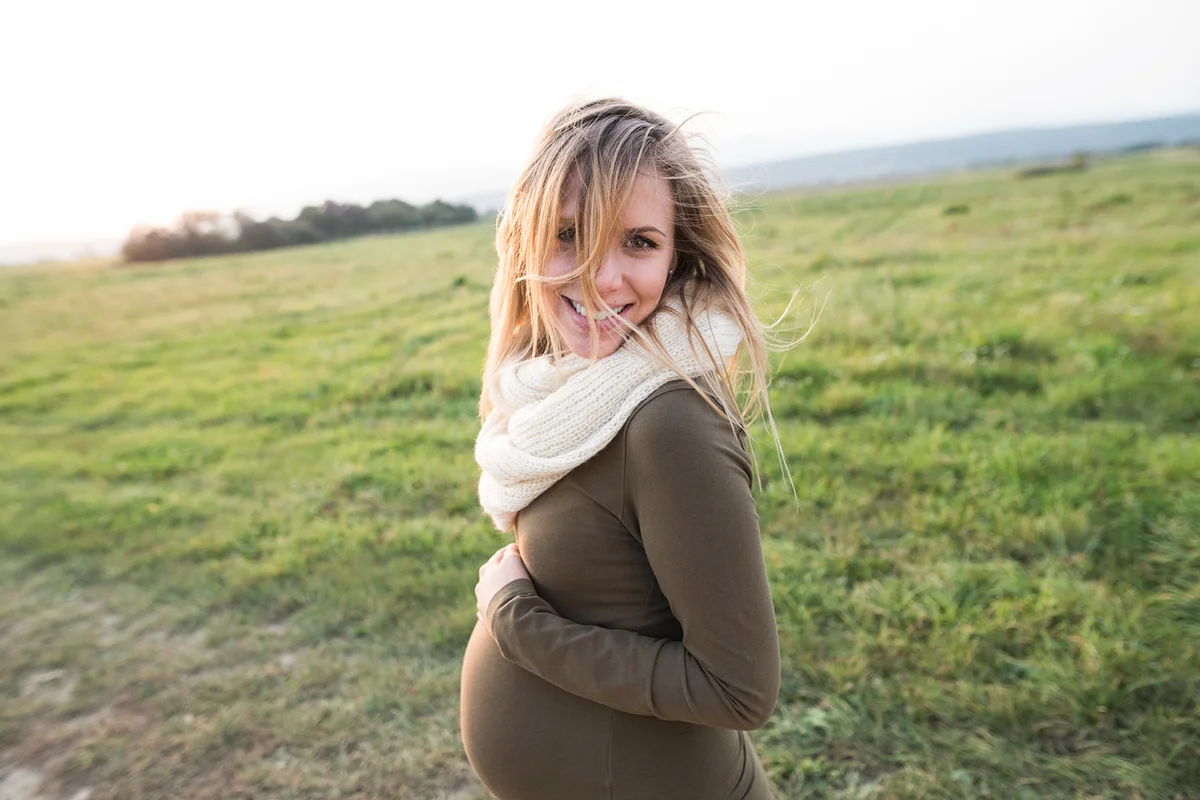 Smiling pregnant woman in rural landscape