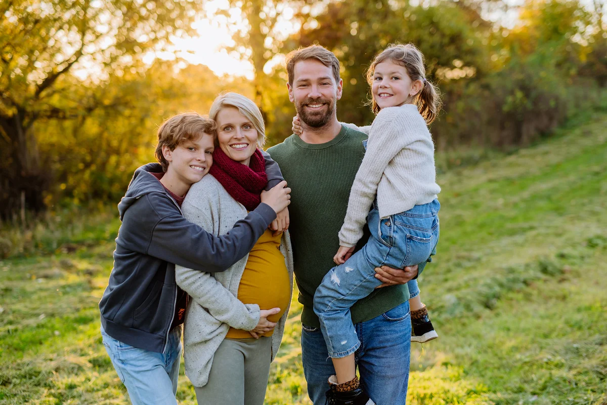 Happy family posing at meadow during sunset