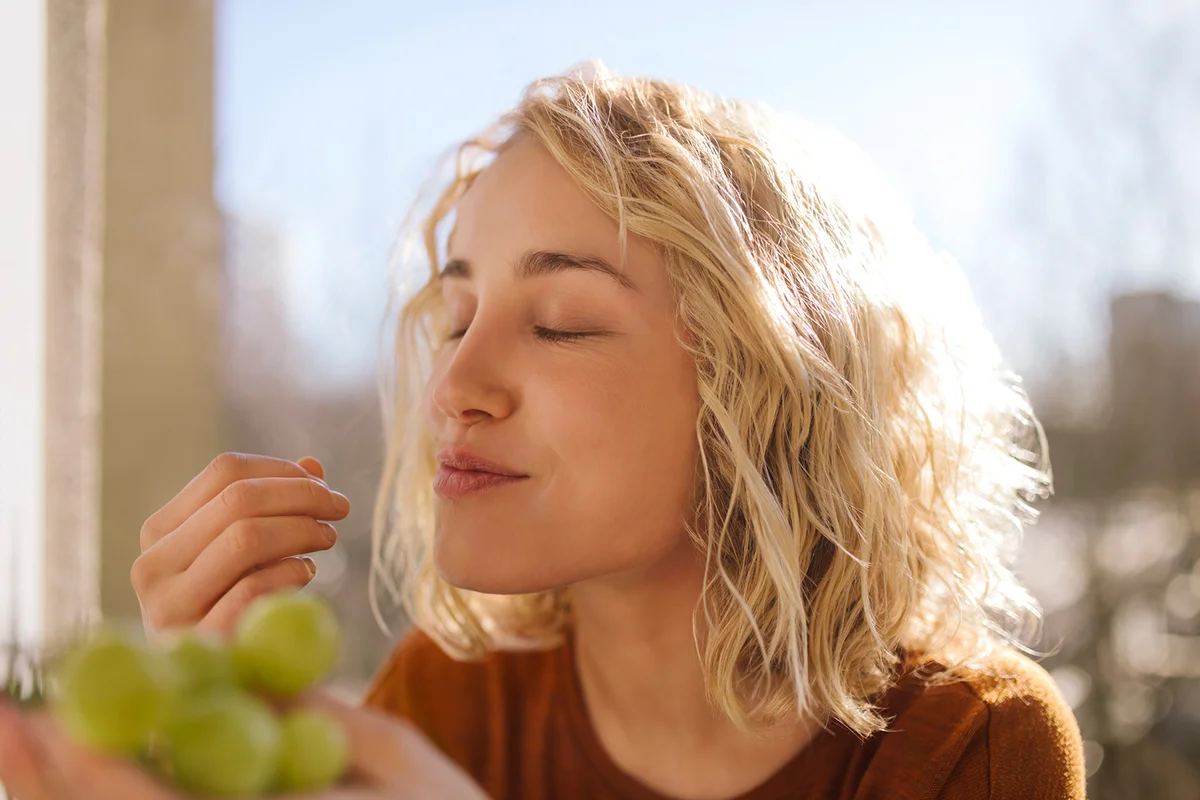 Portrait of young woman eating green grapes