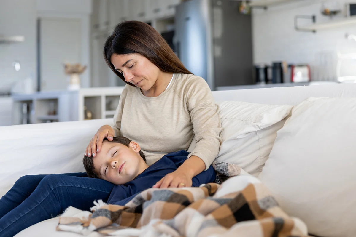 Loving mother pampering her sick son while he is sleeping