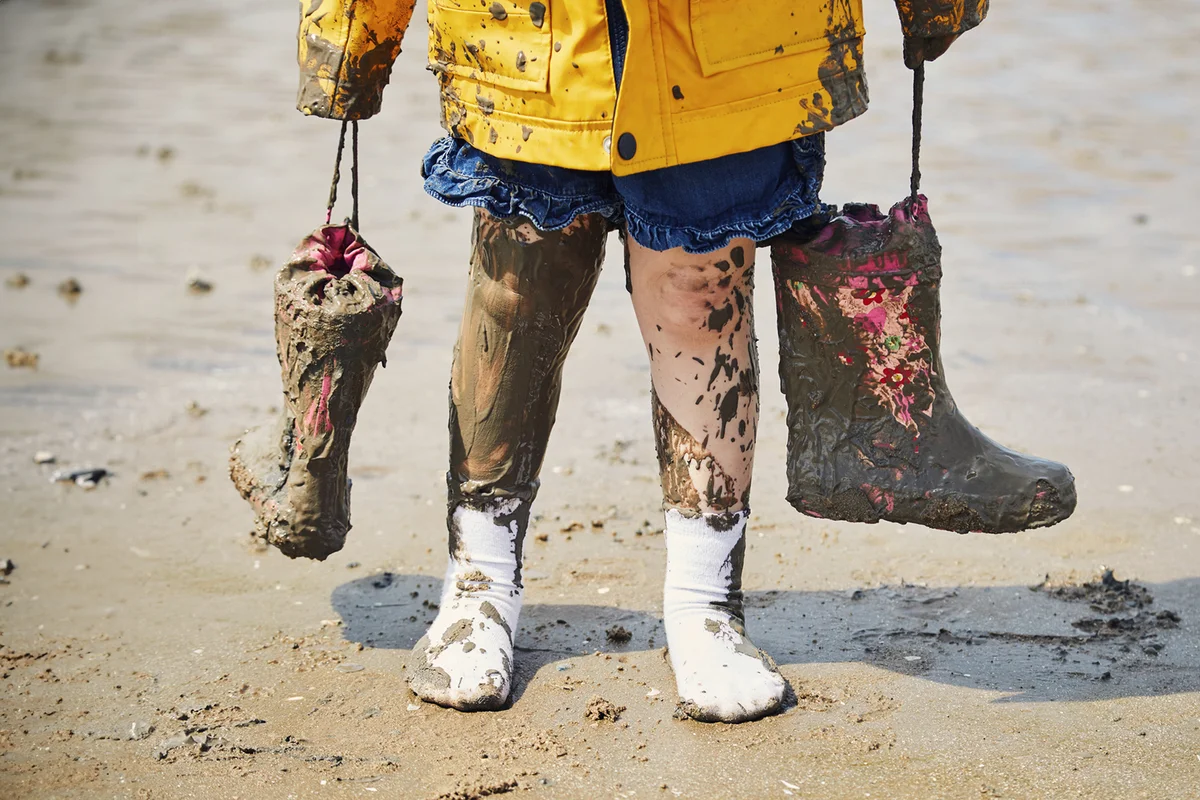 Child holding muddy wellington boots