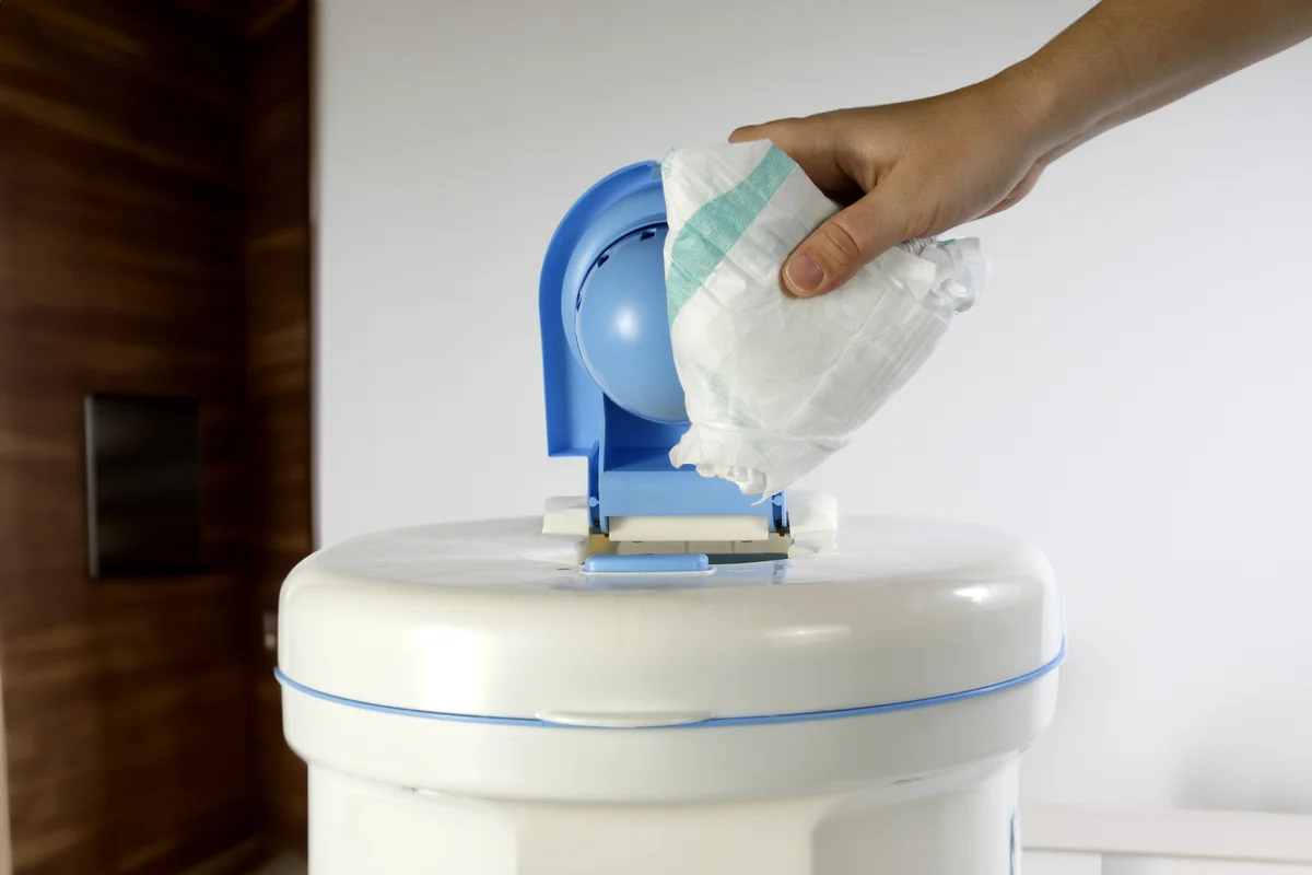 Person inserting used diaper into diaper genie