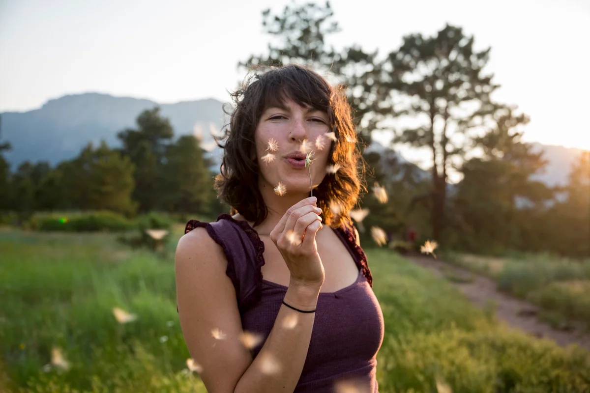 woman blowing a dandelion