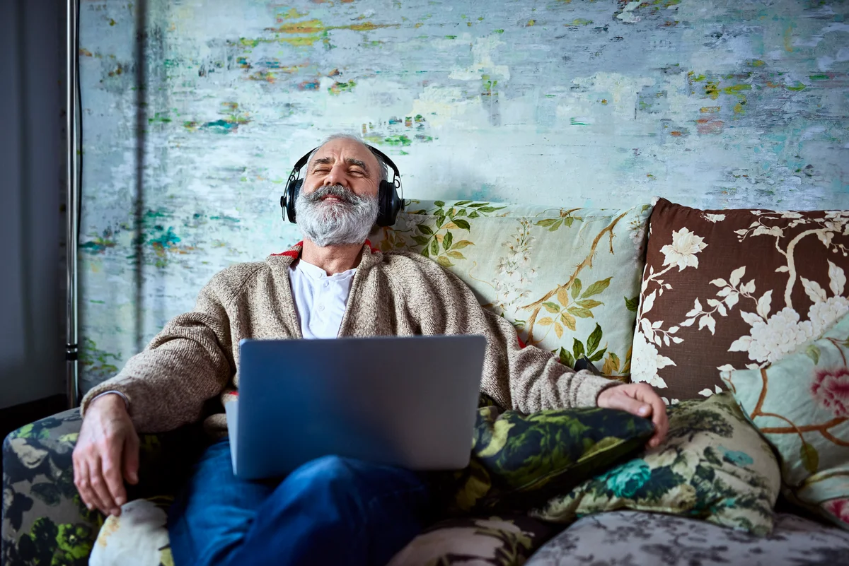 man happily listening to music through headphones