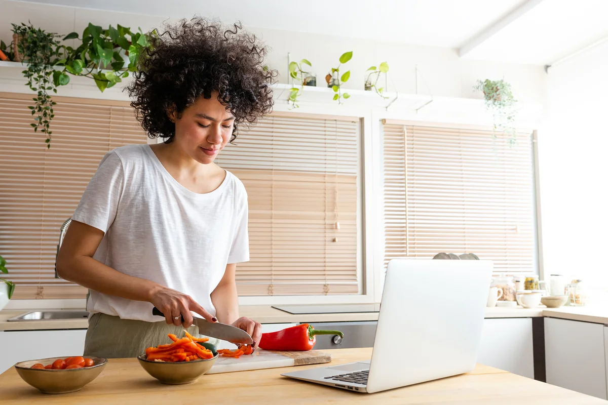 woman cooking following online recipe using laptop