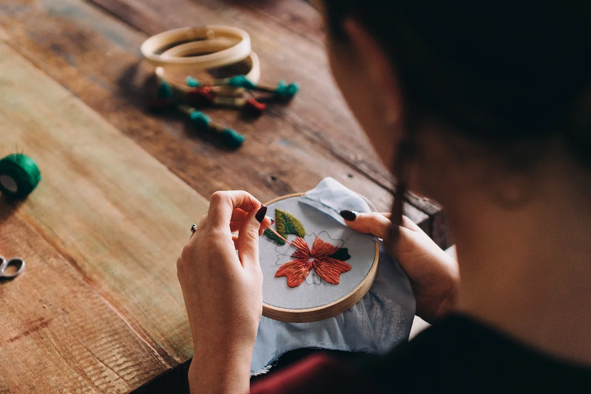 View over shoulder of a woman doing embroidery and colourful needlework