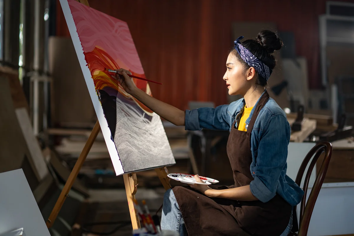 Woman sitting in front of her big painting on canvas