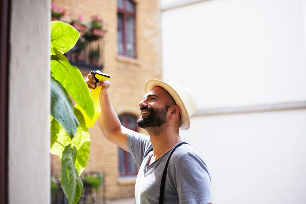 young man watering his plants on his balcony