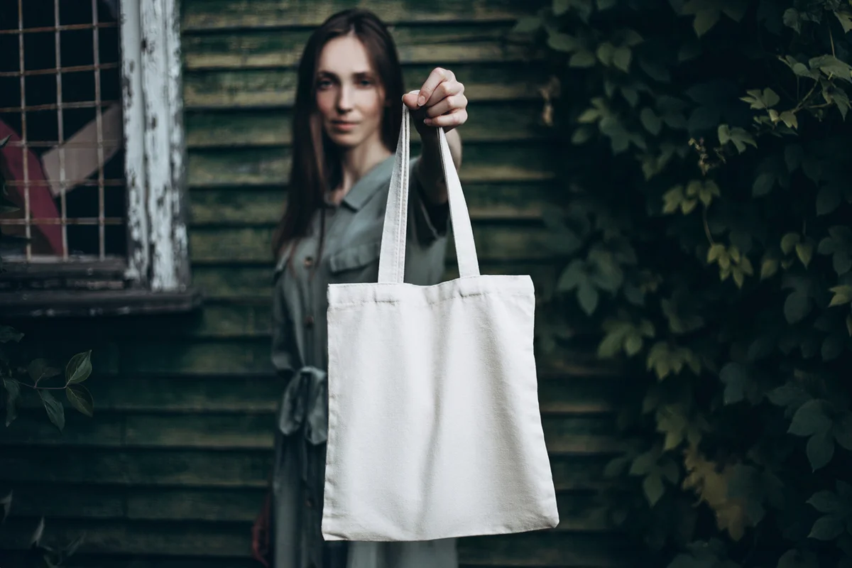 Young woman holding white eco bag in front of her