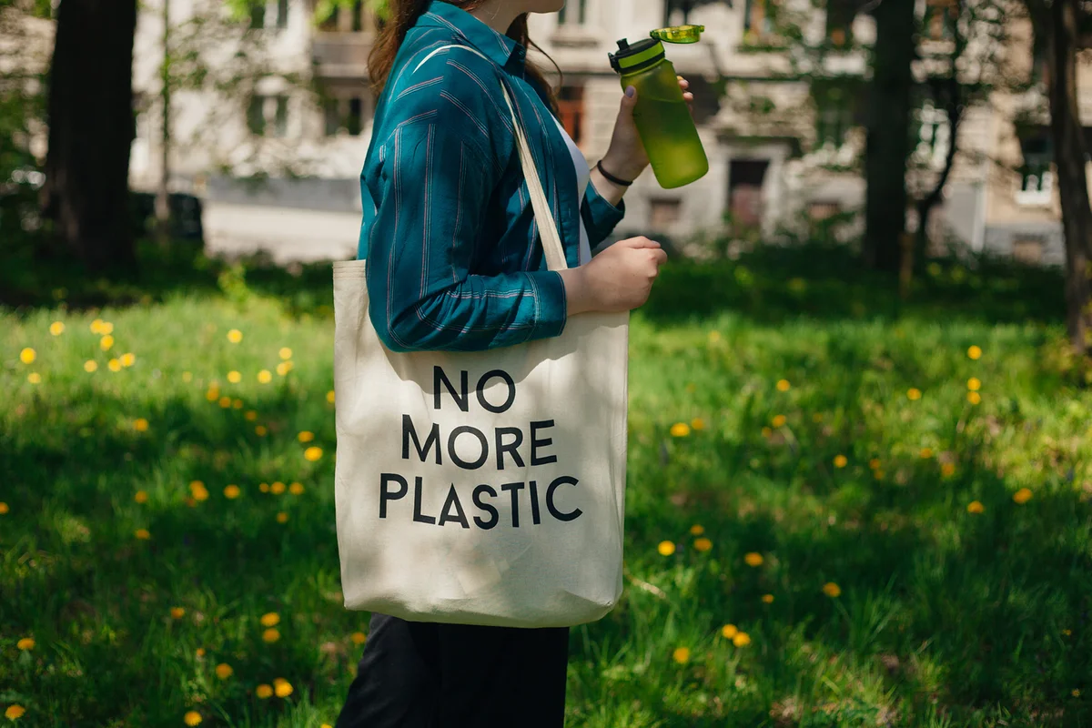 Woman holding reusable cotton zero waste bag with text No More Plastic
