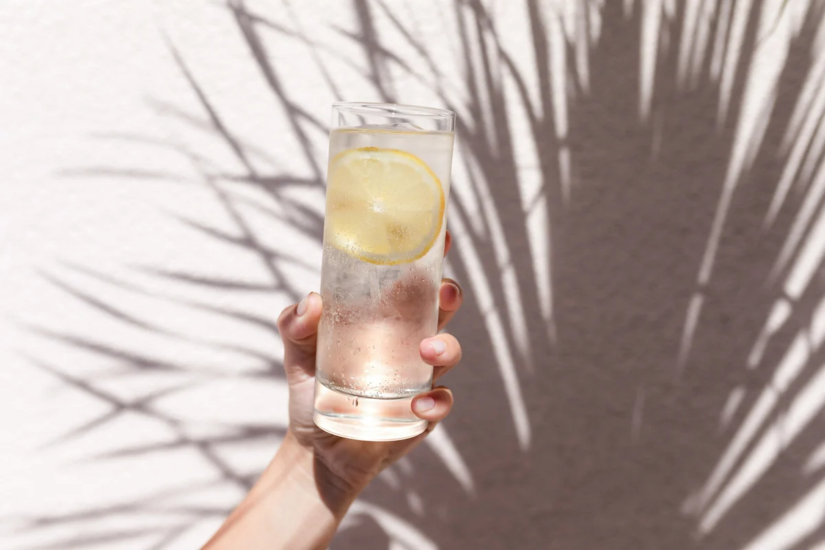 Glass of water with lemon in women's hand