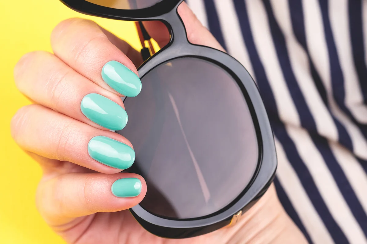 Hand with turquoise nails with sunglasses
