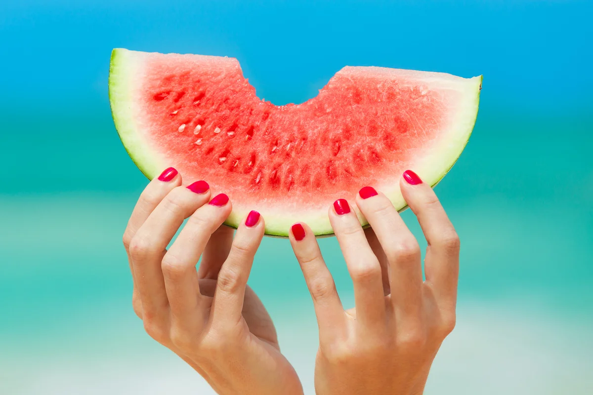 Hand holding watermelon on the beach