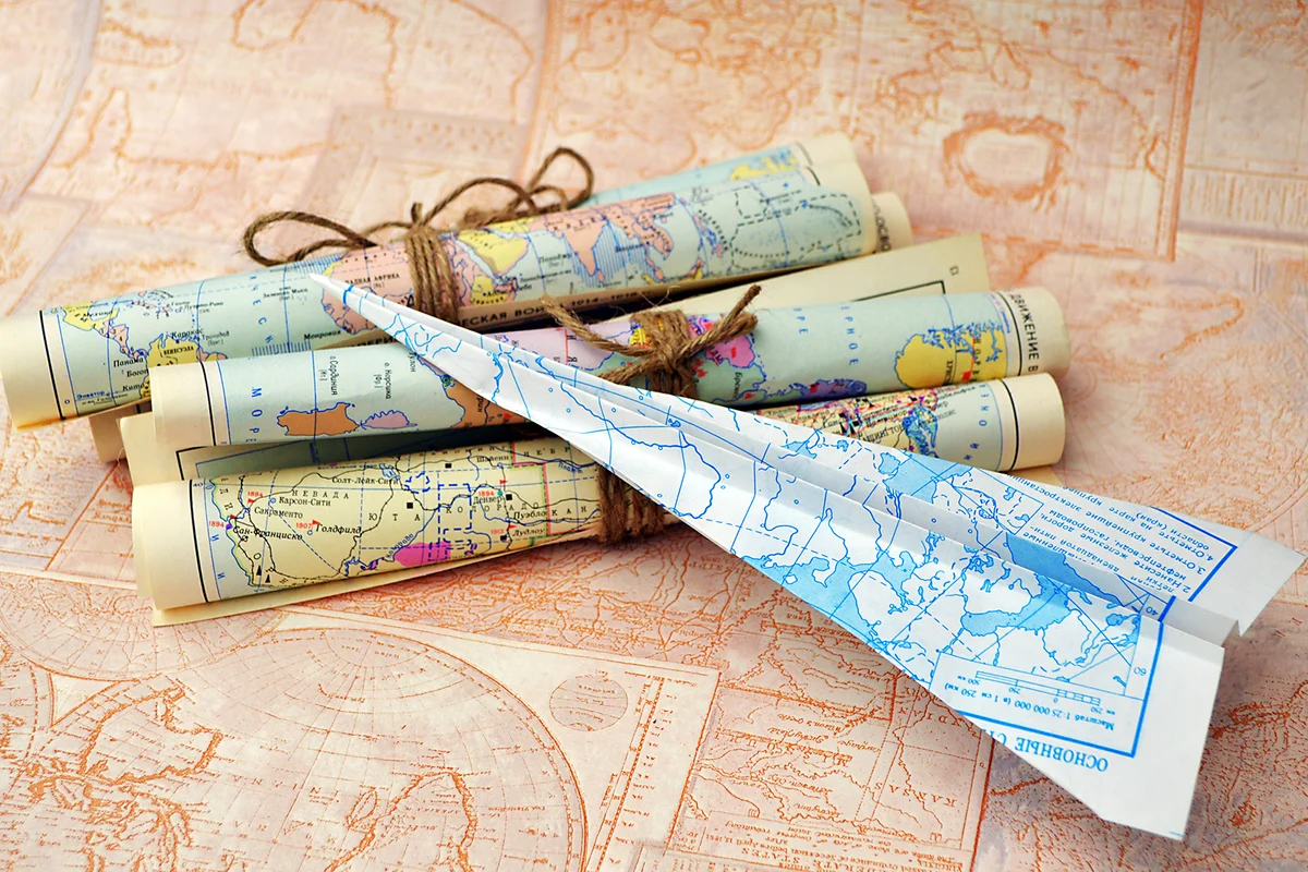 Old rolled maps and paper airplane