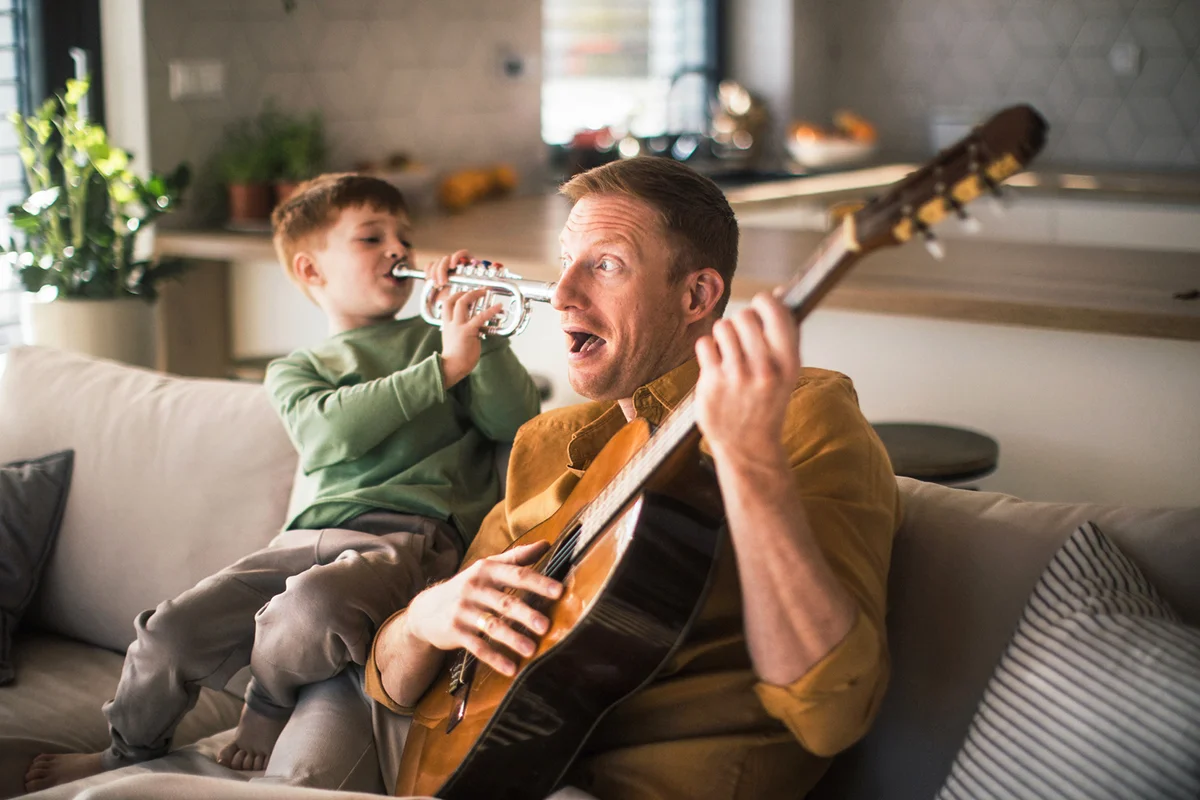Little boy playing on trumpet to his father