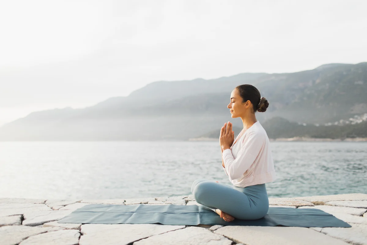 woman meditating by a lake