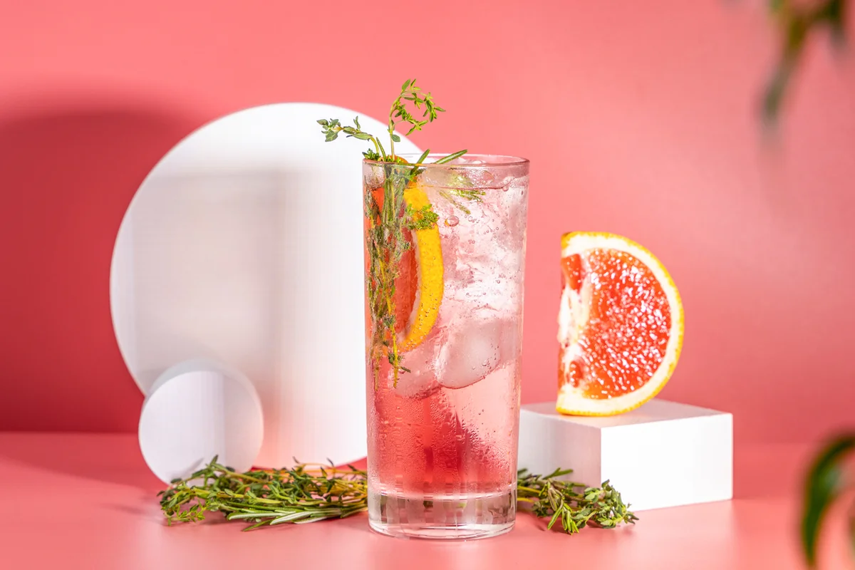 ighball glass of fresh grapefruit cocktail with ice, rosemary and thyme