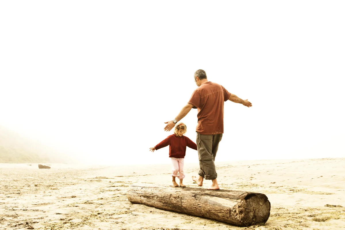 father and daughter balancing on a log