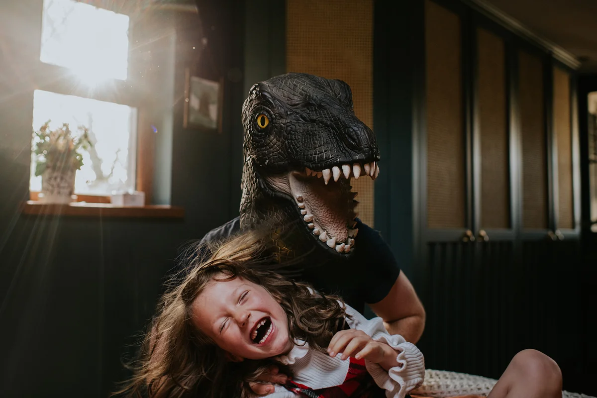 Playful image of a father dressed as dragon playing with his little girl