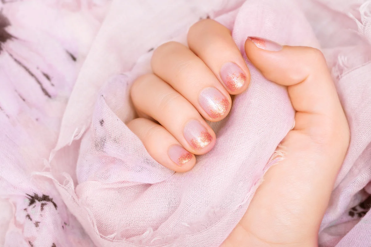 Female hand with pink glitter nail design