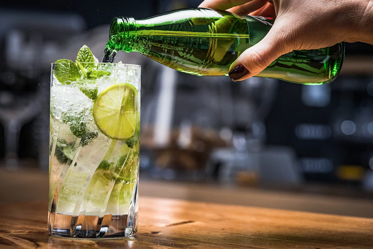 pouring sparkling water into cocktail
