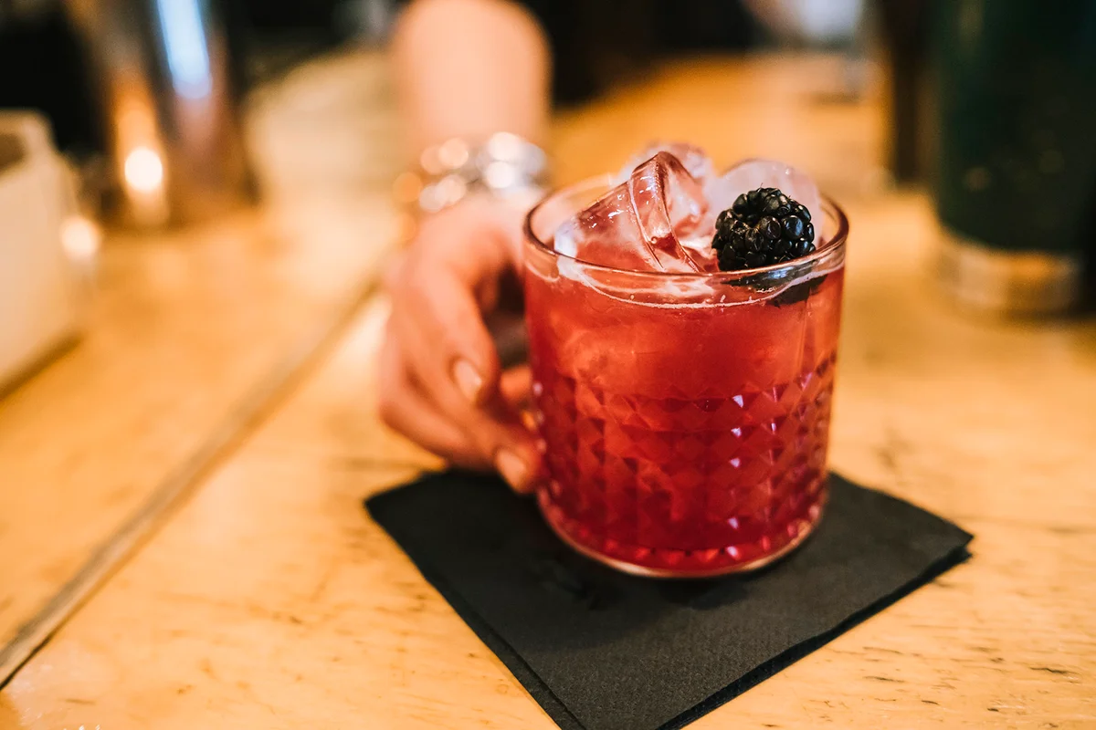 Young barwoman prepares an alcoholic cocktail in the bar