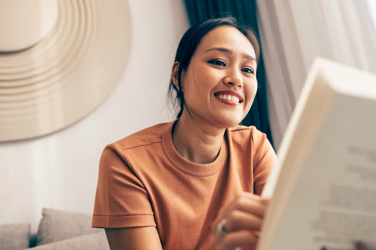 Happy woman sitting on the sofa and reading a book