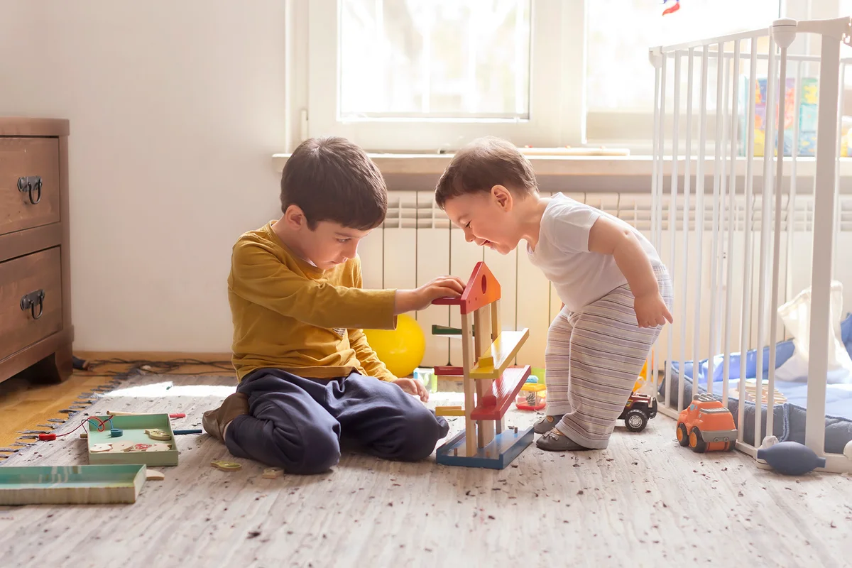 Sibling playing together with wooden toy
