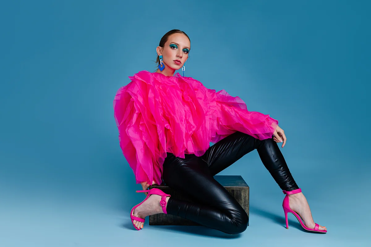 woman wearing leather pants & a bright pink ruffled shirt