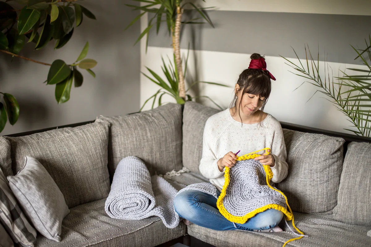 Young woman crocheting in the living-room