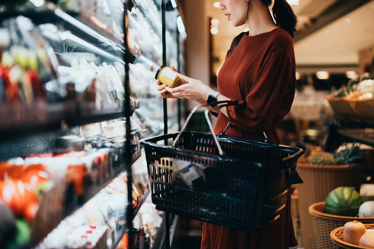 woman with shopping basket reading a label