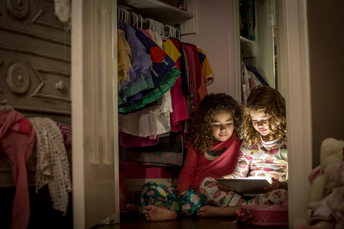 Two girls in a closet with a tablet