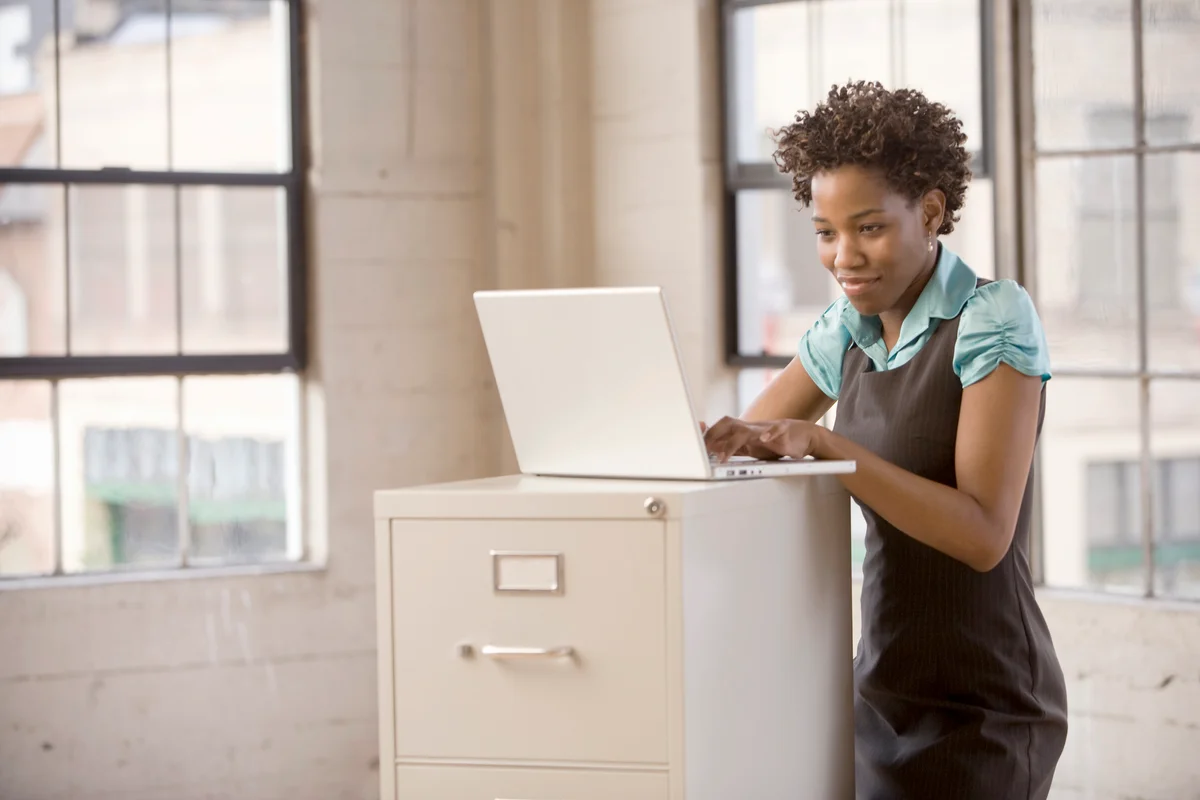 Woman working on laptop on filing cabinet