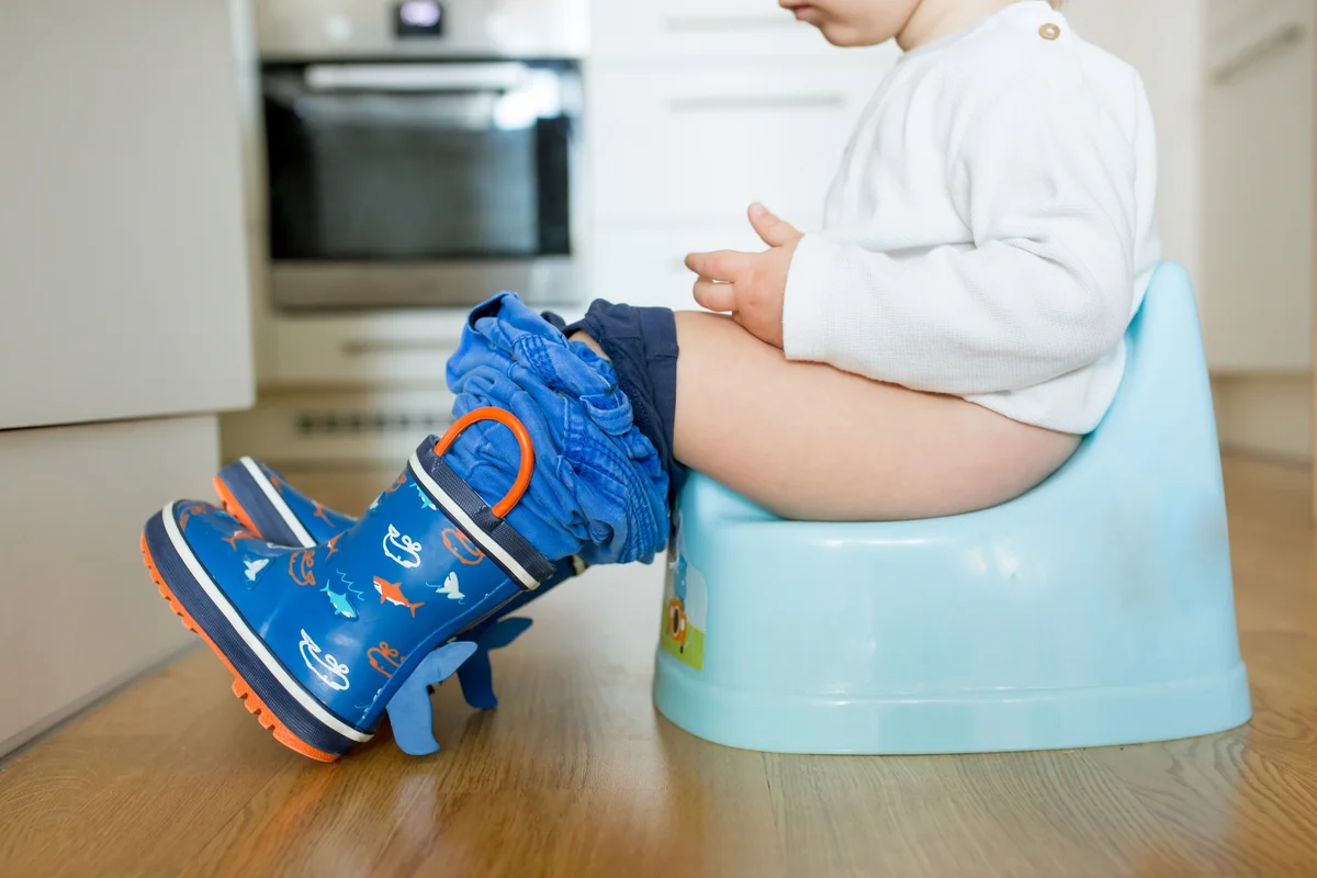 Children's legs in boots, hanging down from a chamber-pot