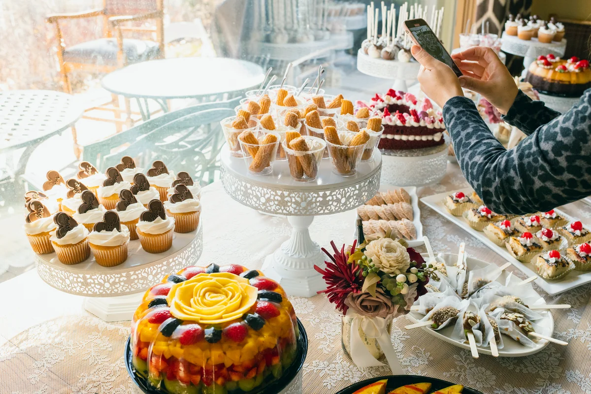 Woman photographing pastries on wedding buffet table