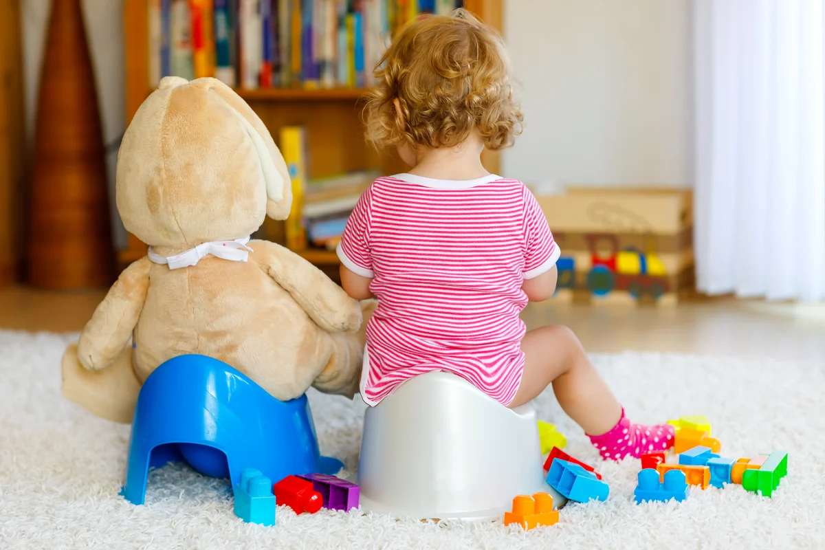 girl on potty next to stuffed bear on potty