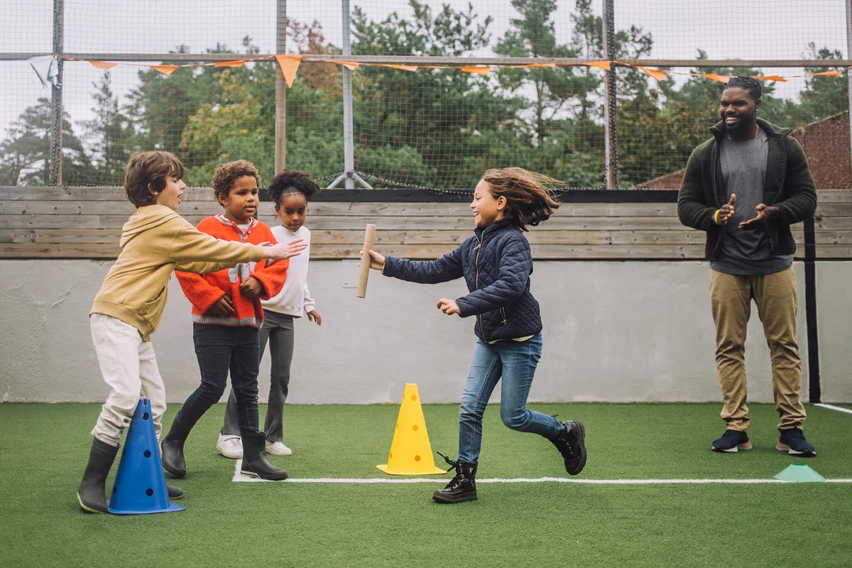 Teacher motivating students doing sports activity in playground